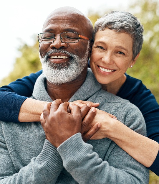Senior woman hugging senior man from behind