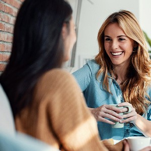 Woman smiling while drinking coffee with friend