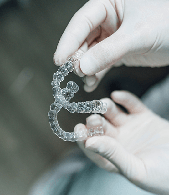 Smiling man holding two Invisalign aligners