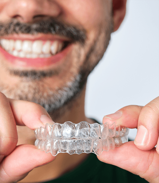 Close up of a woman placing Invisalign over her teeth