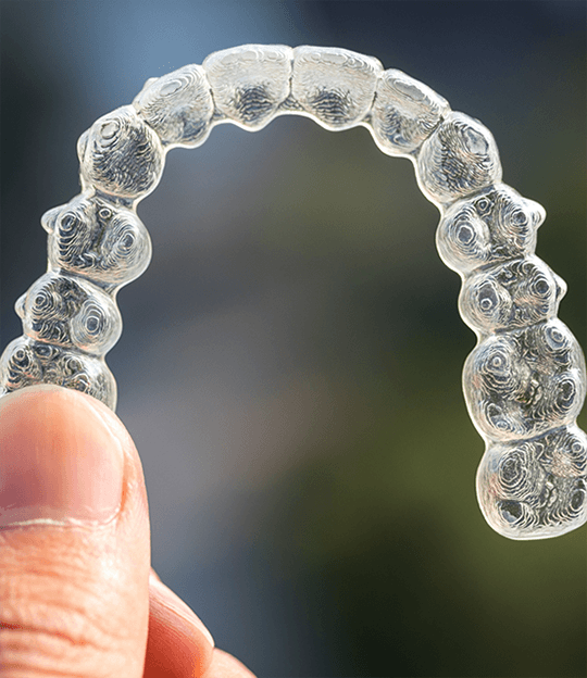 Dentist placing Invisalign over a model of the teeth